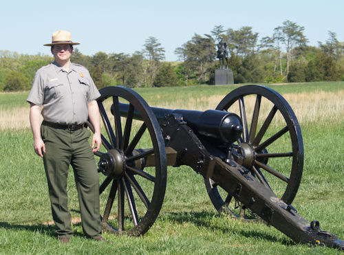 Manassas Battlefield Park Superintendent Ed Clark stands by a federal cannon with a statute of Stonewall Jackson in the background.