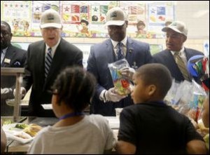 US Secretary of Agriculture Tom Vilsack, Richmond schools Superintendent Dana T. Bedden, and US Rep. Bobby Scott work in the lunch line at Woodville Elementary on March 9, 2015. Photo credit: Richmond Times-Dispatch.