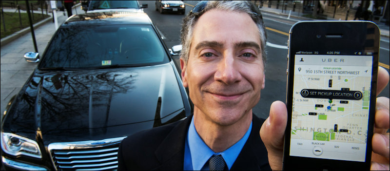 Peter Faris, CEO of Szabo Faris LLC Transportation Solutions, stands in front of one of his vehicles while holding a smart phone with an app that orders up his sedan service February 14, 2013 in Washington, DC. Faris, an independent driver who works with Uber, a technology firm which has created a mobile app which allows consumers to use their device to request a nearby taxi or limousine. Uber is among a number of apps which are being deployed in cities in the United States and worldwide. AFP Photo/Paul J. Richards (Photo credit should read PAUL J. RICHARDS/AFP/Getty Images)