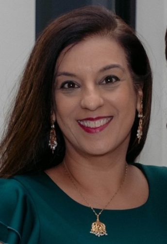 Neena Moorjani smiling, wearing a green dress and earrings, promoting financial literacy and education.