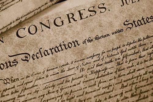 Close-up view of the Declaration of Independence, highlighting the words 'Congress' and 'Declaration of the thirteen united States.' The document is aged and features ornate typography.