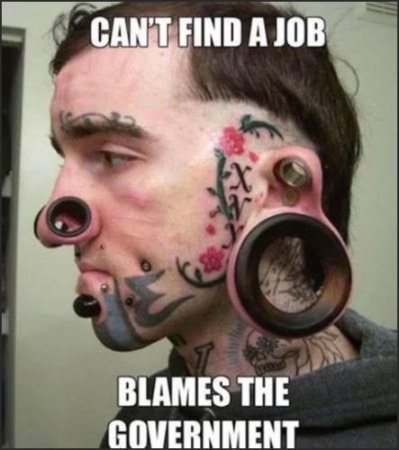 A person with extensive facial tattoos and large ear gauges, featuring text that humorously states, 'CAN'T FIND A JOB BLAMES THE GOVERNMENT.'