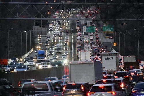 Heavy traffic congestion on a major highway during rush hour, with numerous vehicles including cars and trucks occupying multiple lanes.