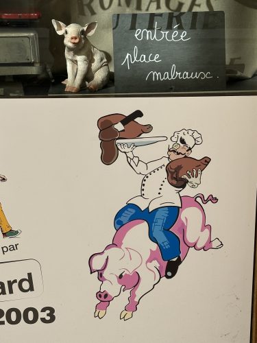 A cartoonish chef riding a pig, holding a piece of meat in one hand and wearing a chef's hat, next to a small decorative pig and a chalkboard sign that says 'entr&eacute;e place malraux'.