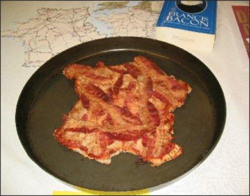 A plate of crispy bacon strips displayed on a round tray, with a map and a book titled 'Francis Bacon' in the background.