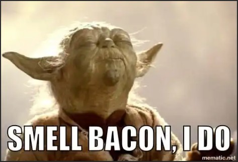 A humorous image of a character resembling a small, green alien with large ears, eyes closed and a pleased expression, with the text 'SMELL BACON, I DO' overlayed.