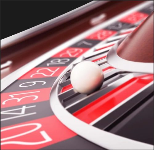 Close-up of a roulette wheel with a white ball resting on the edge of the betting area.