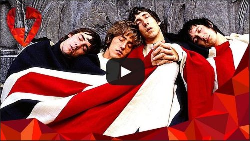 A group of four musicians relaxes on the ground, covered by a large Union Jack blanket, with their heads resting against each other, exuding a laid-back and cozy atmosphere.