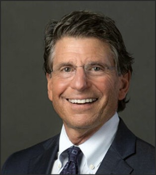 Professional portrait of a middle-aged man in a suit, smiling at the camera.
