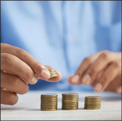 A person stacking coins into piles on a table.