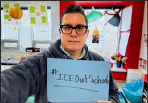 Person holding a sign that reads '#ICEOutSchools' in a classroom setting.