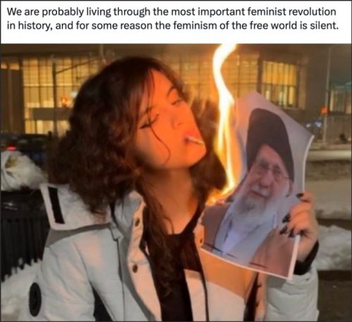 A person with dark hair and a white coat is holding and setting fire to a photograph of a man while smoking a cigarette. In the background, city lights are visible. A caption above the image discusses a significant feminist revolution.