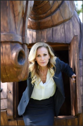 A woman in business attire emerging from a large wooden horse sculpture.