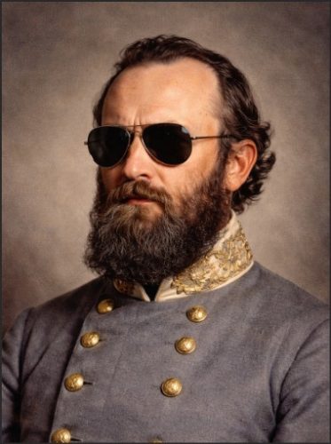 A historical portrait of a man with a beard, wearing a military uniform and sunglasses, conveying a bold and confident demeanor.