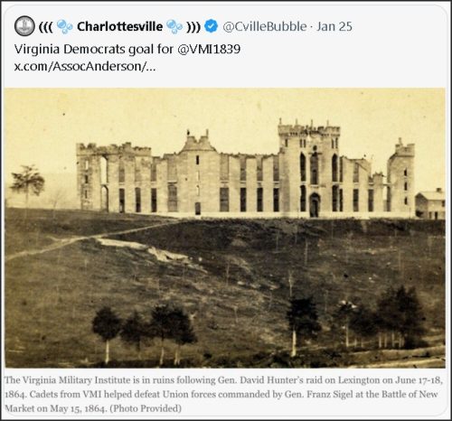 Black and white image of the Virginia Military Institute in ruins, with historic buildings showing structural damage, set against a tree-lined landscape.