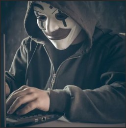A person wearing a hoodie and a mask is typing on a laptop, suggesting a theme of hacking or anonymity.