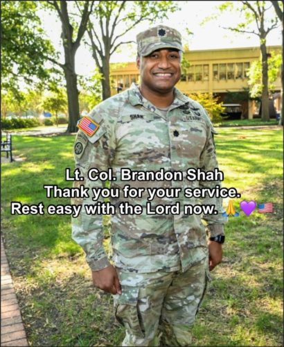 A smiling military officer in full camouflage uniform stands outdoors, surrounded by trees and greenery, with a message of gratitude and remembrance displayed on the image.