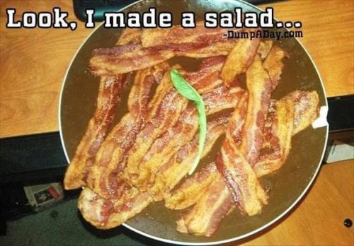 A bowl filled with strips of crispy bacon, humorously labeled as a salad with a small green leaf on top.