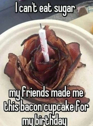 A humorous birthday photo featuring a cupcake made of bacon shaped like a rose, adorned with a birthday candle, with text expressing the sentiment of not being able to eat sugar.