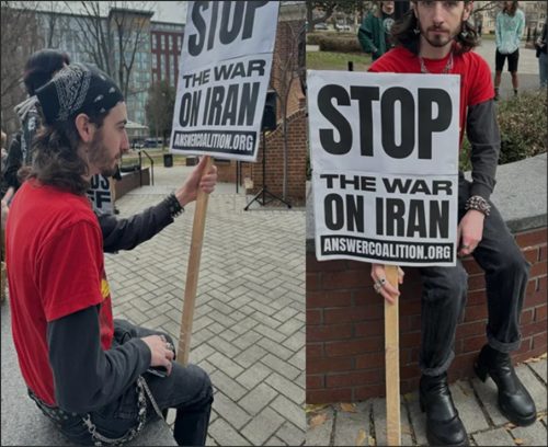 A young activist wearing a red shirt and black pants holds a sign that reads 'STOP THE WAR ON IRAN' while sitting on a bench at a protest.