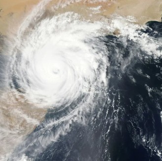 Satellite image of a large hurricane swirling over ocean waters near land.