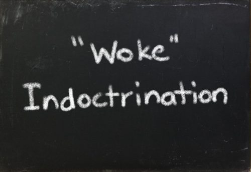 "Woke" Indoctrination written in white chalk on a blackboard.